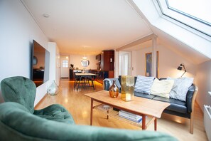 A modern living room with a sofa, a coffee table, and a dining area in the background. - Harbour View - Marina - City Centre (Tórshavn)
