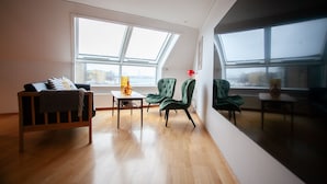 A spacious living room with a high ceiling, large windows, and a view of the city. - Harbour View - Marina - City Centre (Tórshavn)