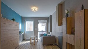 Un appartement moderne avec un plancher en bois, un canapé, une petite table et un meuble.