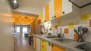 Une cuisine avec des meubles de couleur jaune et blanche, un évier et un plan de travail sur lequel sont posés des ustensiles de cuisine.