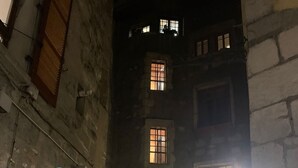 A narrow alleyway with a building featuring multiple windows and a door. A bicycle is parked in front of the building. - Modern duplex loft in the heart of Annecy's old town for 10 people (annecy)