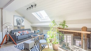 A modern living room with a grey sofa, a fan, a potted plant, and a skylight. - Modern duplex loft in the heart of Annecy's old town for 10 people (annecy)