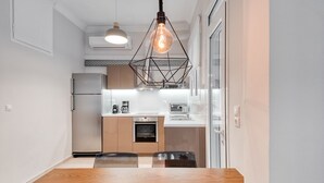 Een moderne keuken met een houten eettafel, roestvrijstalen apparatuur en hangende lampen.