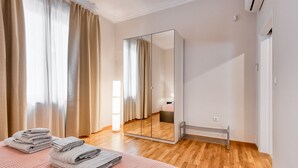 Een hotelkamer met een bed, een grote spiegel, een radiator en een raam met gordijnen.