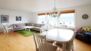 A spacious living room with a dining area, a sofa, a rocking chair, and a chandelier. - Liljulon - Views - Location (Ljosa)