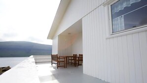 A modern house with a balcony overlooking a body of water and hills. - Liljulon - Views - Location (Ljosa)
