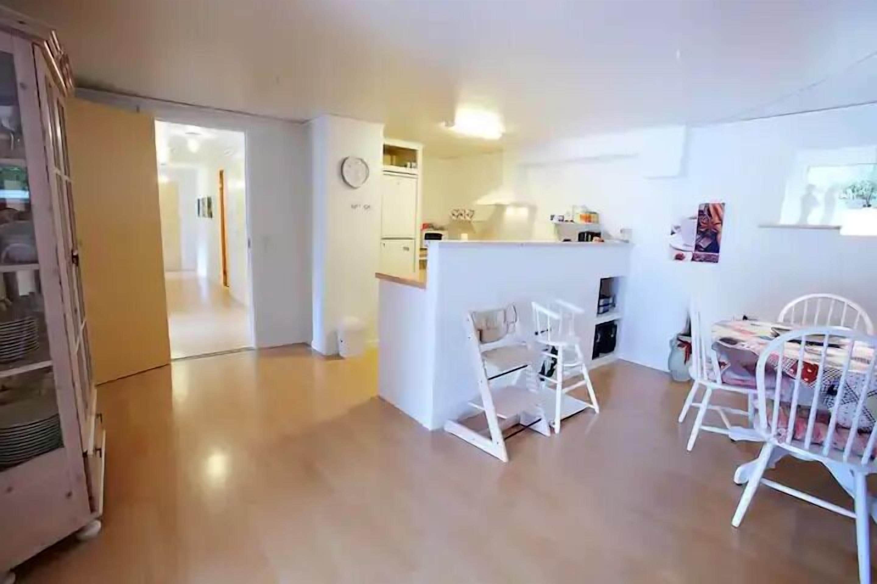 A bright, open-plan living area with a kitchen, dining table, and chairs.