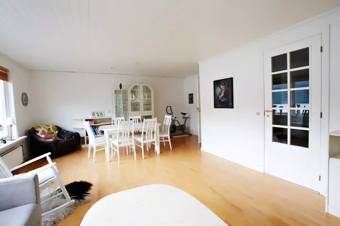 Un salon spacieux avec un coin repas, une porte blanche et un tableau accroché au mur.