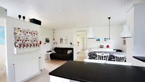 A modern, well-lit living space with a black dining table, white chairs, a black sofa, and a white radiator. - Liljulon - Views - Location (Ljosa)