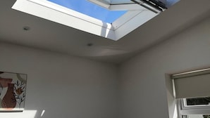 Una habitación con tragaluces, una ventana y una lámpara fijada a la pared.