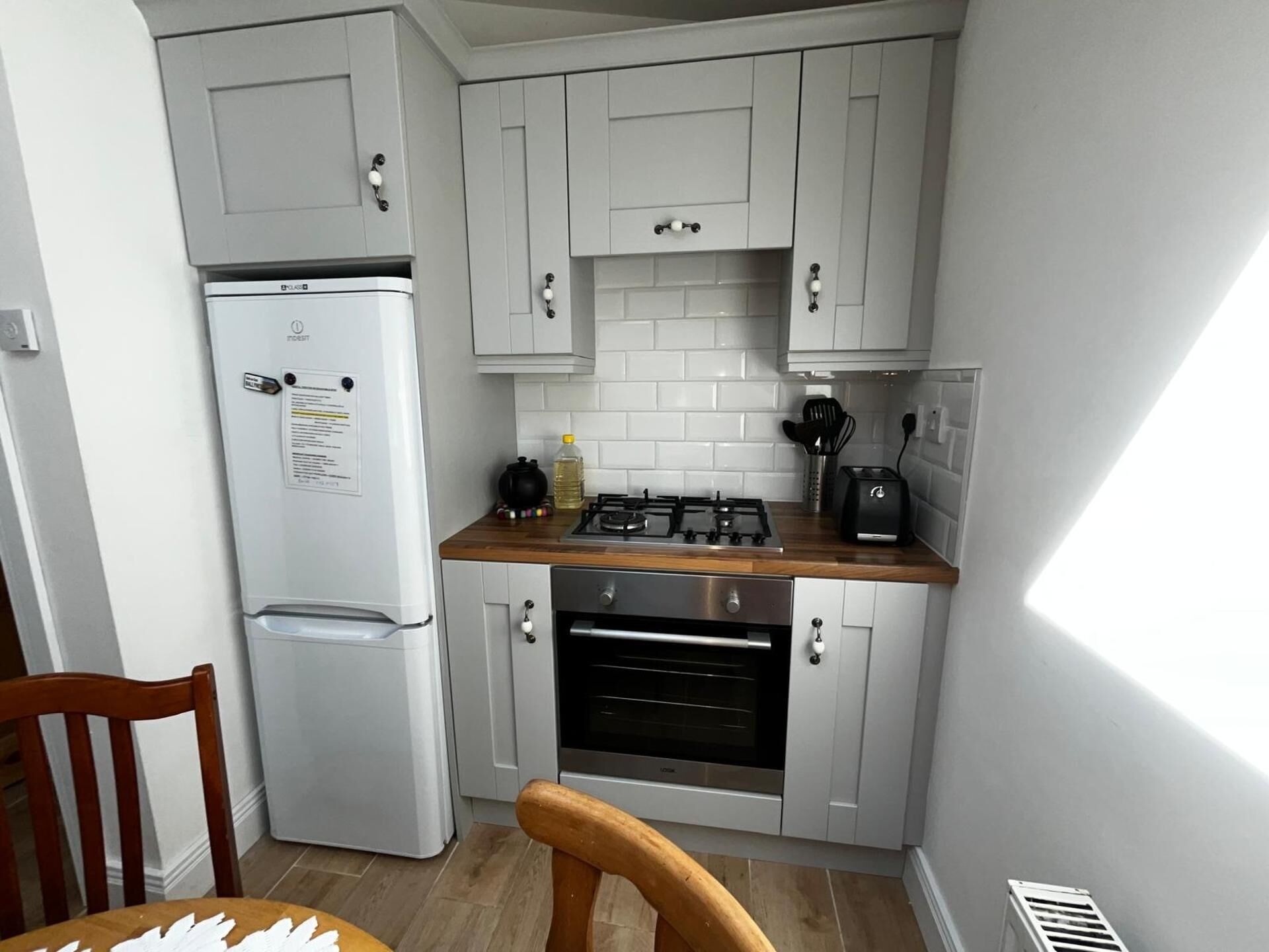 A compact kitchen with a refrigerator, oven, and gas stove.