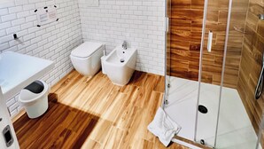 Un bagno moderno con cabina doccia in vetro, lavandino bianco e bidet.