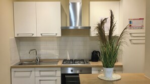 Una cucina moderna con mobili bianchi, una cappa aspirante in acciaio inossidabile, un fornello a gas e un forno integrato.