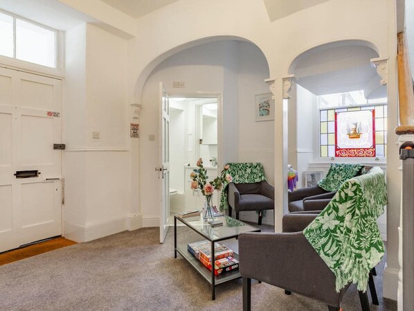 A room with a glass coffee table, two armchairs, a sofa, and a door with a sign.