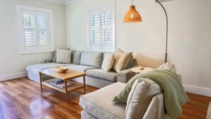 Ein Wohnzimmer mit einem Ecksofa, einem Couchtisch, einem Beistelltisch und einer Stehlampe.