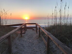 Un muelle de madera que conduce a una playa al atardecer.