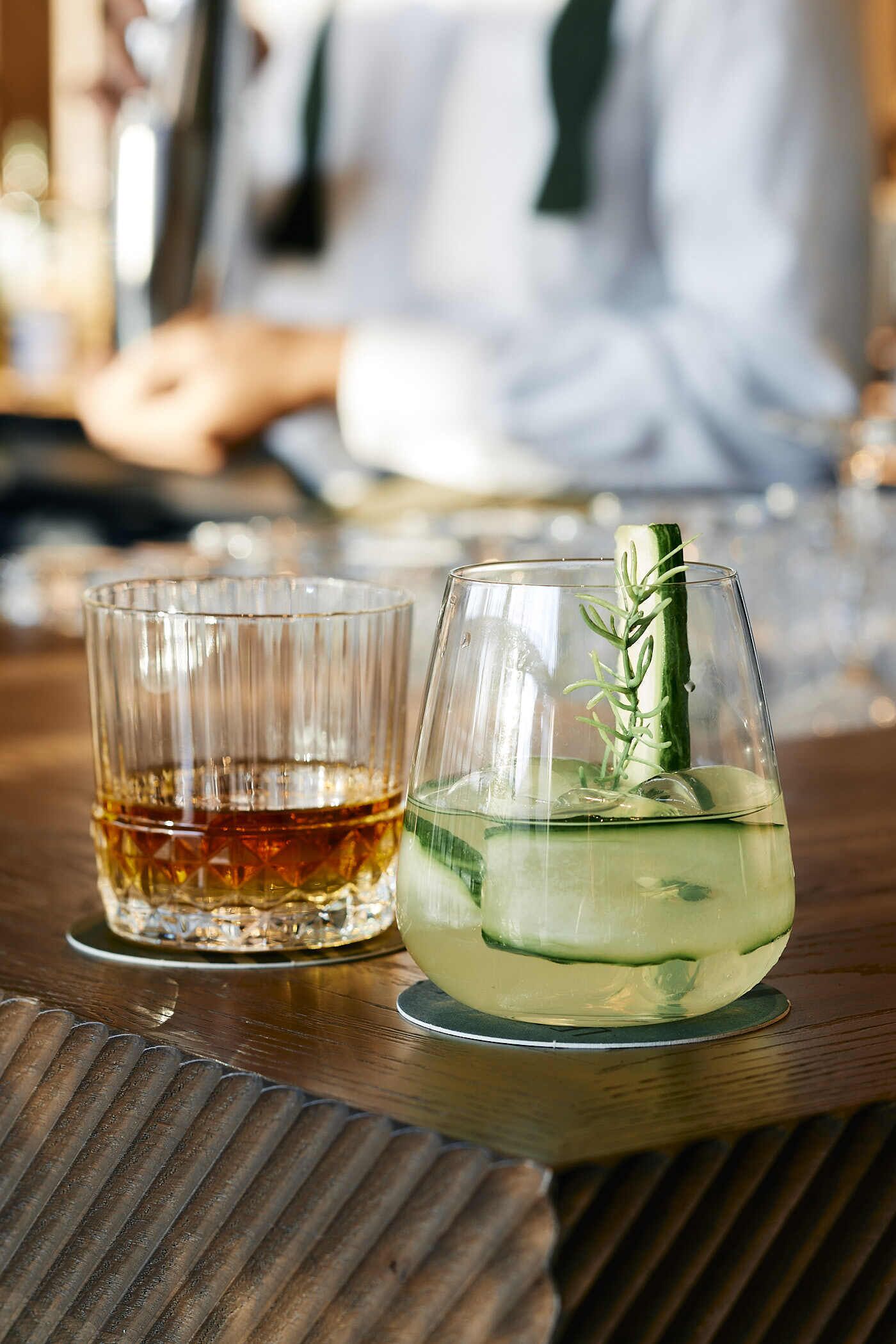 Två glas med dryck står på en bardisk av trä.