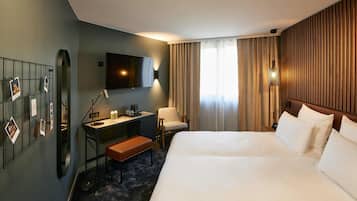 A hotel room with a bed, a desk with a chair, a TV, and a wall-mounted mirror.