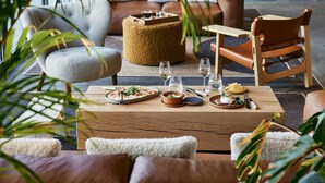 A cozy dining area with a wooden table set for two, surrounded by comfortable seating and a view of the ocean. - Le Bellune Paris Hotel & Spa (Paris)
