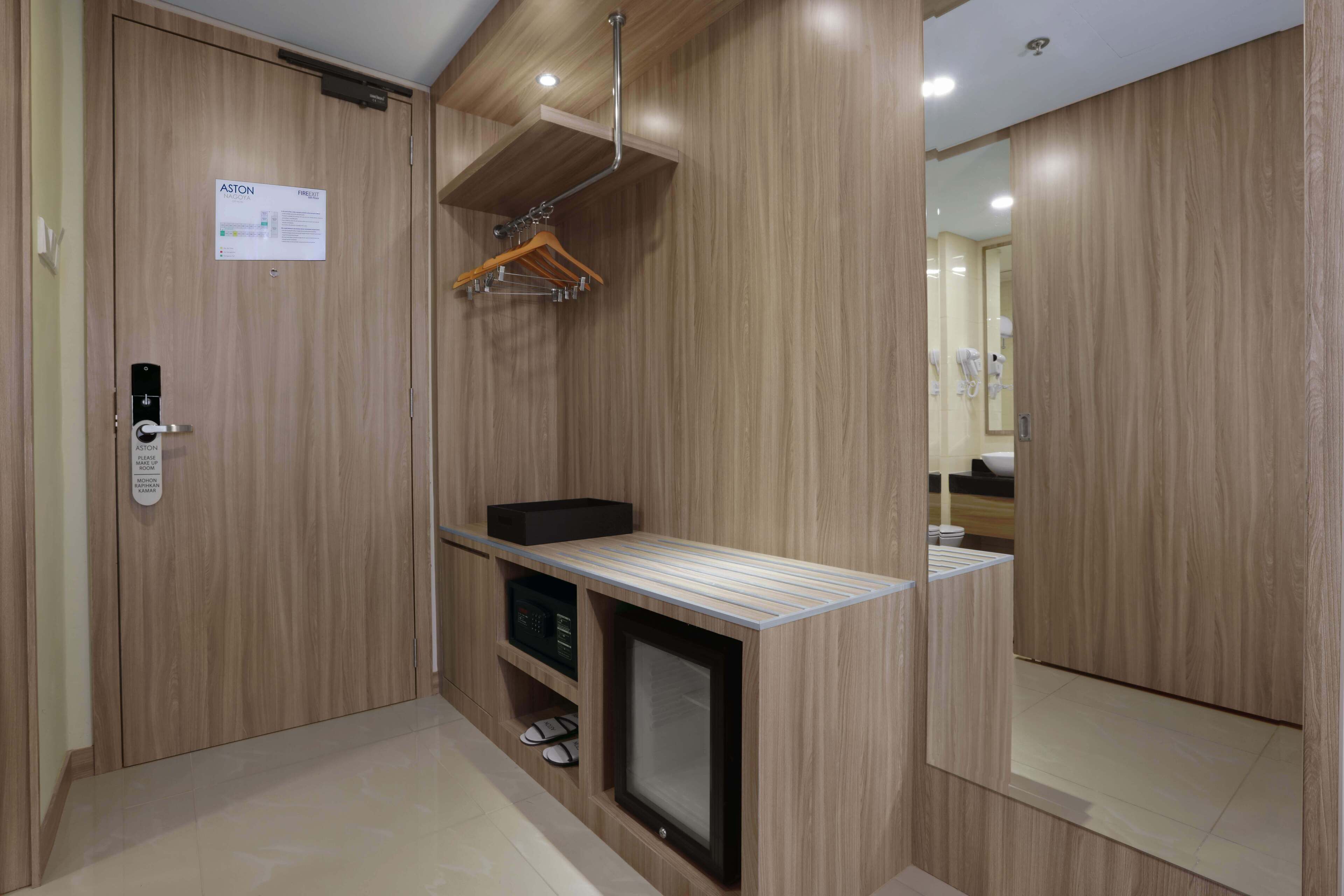 A modern bathroom with wooden paneling, a mirror, a towel rack, and a small shelf with a black box and slippers.