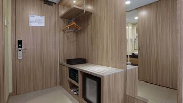 A modern bathroom with wooden paneling, a mirror, a towel rack, and a small shelf with a black box and slippers.