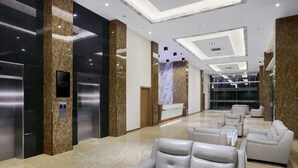 A modern lobby with marble flooring, a reception desk, and a seating area with leather chairs.