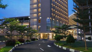 A high-rise hotel with a prominent "ASTON" sign, featuring a modern design with numerous windows and a well-lit facade.