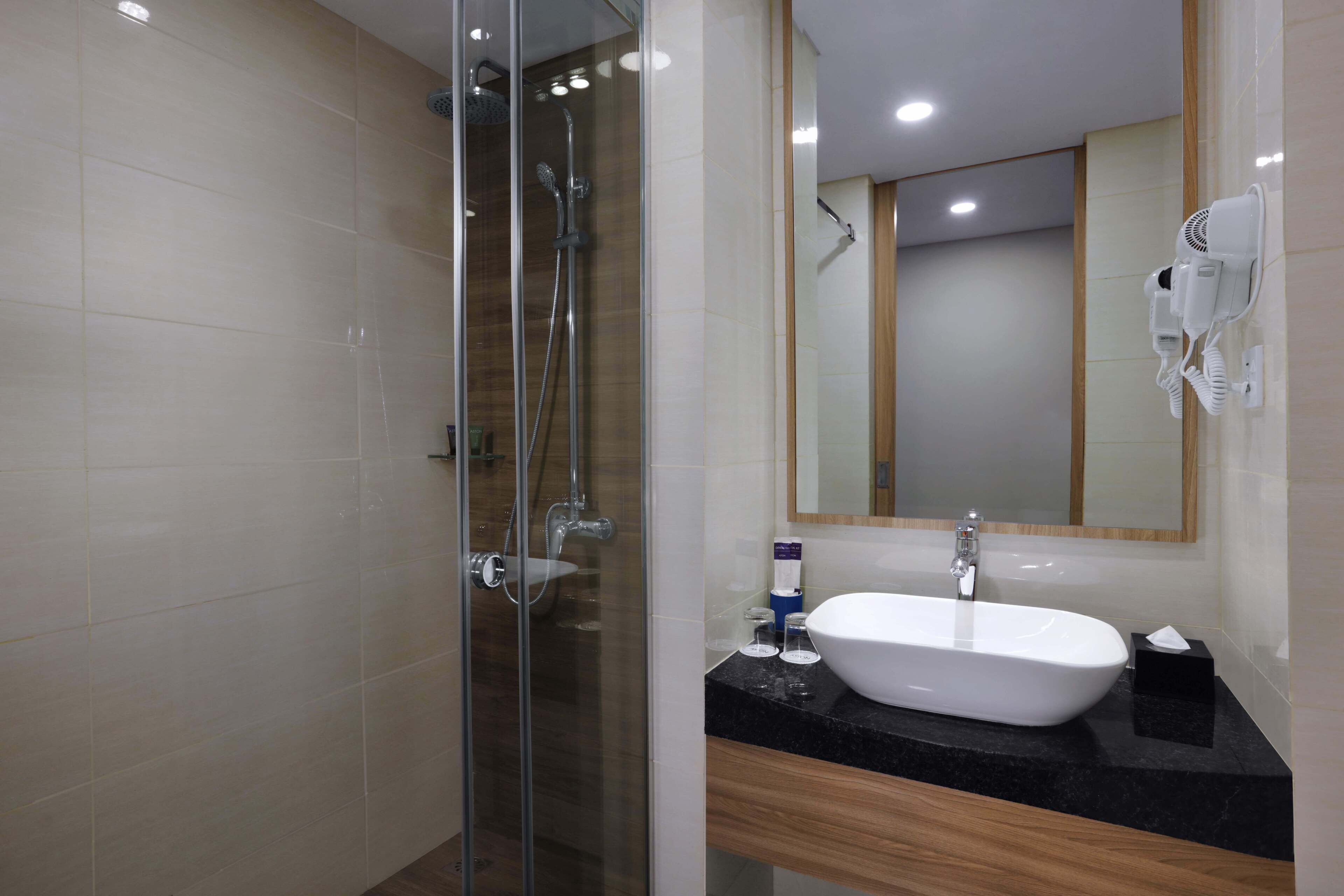A modern bathroom with a glass-enclosed shower, a white sink, and a large mirror.