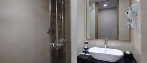 A modern bathroom with a glass-enclosed shower, a white sink, and a large mirror.