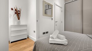 A modern bedroom with a bed, a white dresser, a mirror, and a wardrobe. - Lovely 1 Bedroom Apartment in Regents Park London by MySquare (London)