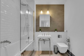Une salle de bain moderne avec une douche à parois de verre, un lavabo blanc et des toilettes.