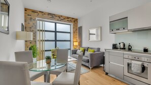 A modern kitchen with a built-in oven and a dining area with a glass table and chairs. - Lovely 1 Bedroom Apartment in Regents Park London by MySquare (London)