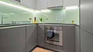 A modern kitchen with grey cabinets, a stainless steel oven, and a glass backsplash. - Lovely 1 Bedroom Apartment in Regents Park London by MySquare (London)