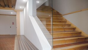 Eine Holztreppe mit Glastrennstäben, eine weiße Wand und eine Tür mit einem Rauchverbot-Schild.