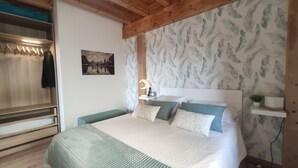 Ein Schlafzimmer mit einem Bett, einem Nachttisch, einer Lampe, einem Bild an der Wand und einem Kleiderschrank.