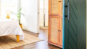Une chambre à coucher avec un lit, une table de chevet, une lampe et une plante en pot.