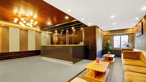 A hotel lobby with a reception desk, seating area, and a large window. - Treebo Spring Brook (Guwahati)