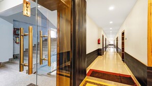 A modern hotel lobby with a glass entrance, a staircase, and a long corridor. - Treebo Spring Brook (Guwahati)