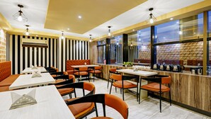 A restaurant interior with striped walls, orange seating, and a wooden accent wall. - Treebo Spring Brook (Guwahati)