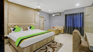A hotel room with a bed, a sofa, a coffee table, and a desk. - Treebo Spring Brook (Guwahati)