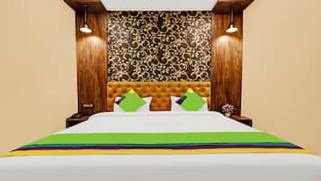 A hotel room with a tufted headboard, a patterned wallpaper, and a bed with a multicolored bedspread.