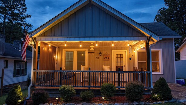 A two-story house with a porch, a flag, and a well-lit front yard. - Etowah's Cottage - dog friendly, king beds, hiking, rafting, motorcycles (Etowah)
