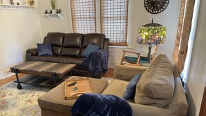 A living room with a brown leather sofa, a beige sofa, a wooden coffee table, and a colorful lamp. - Etowah's Cottage - dog friendly, king beds, hiking, rafting, motorcycles (Etowah)