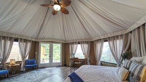 Une chambre spacieuse aménagée comme une tente, avec un grand lit, un bureau et une chaise.