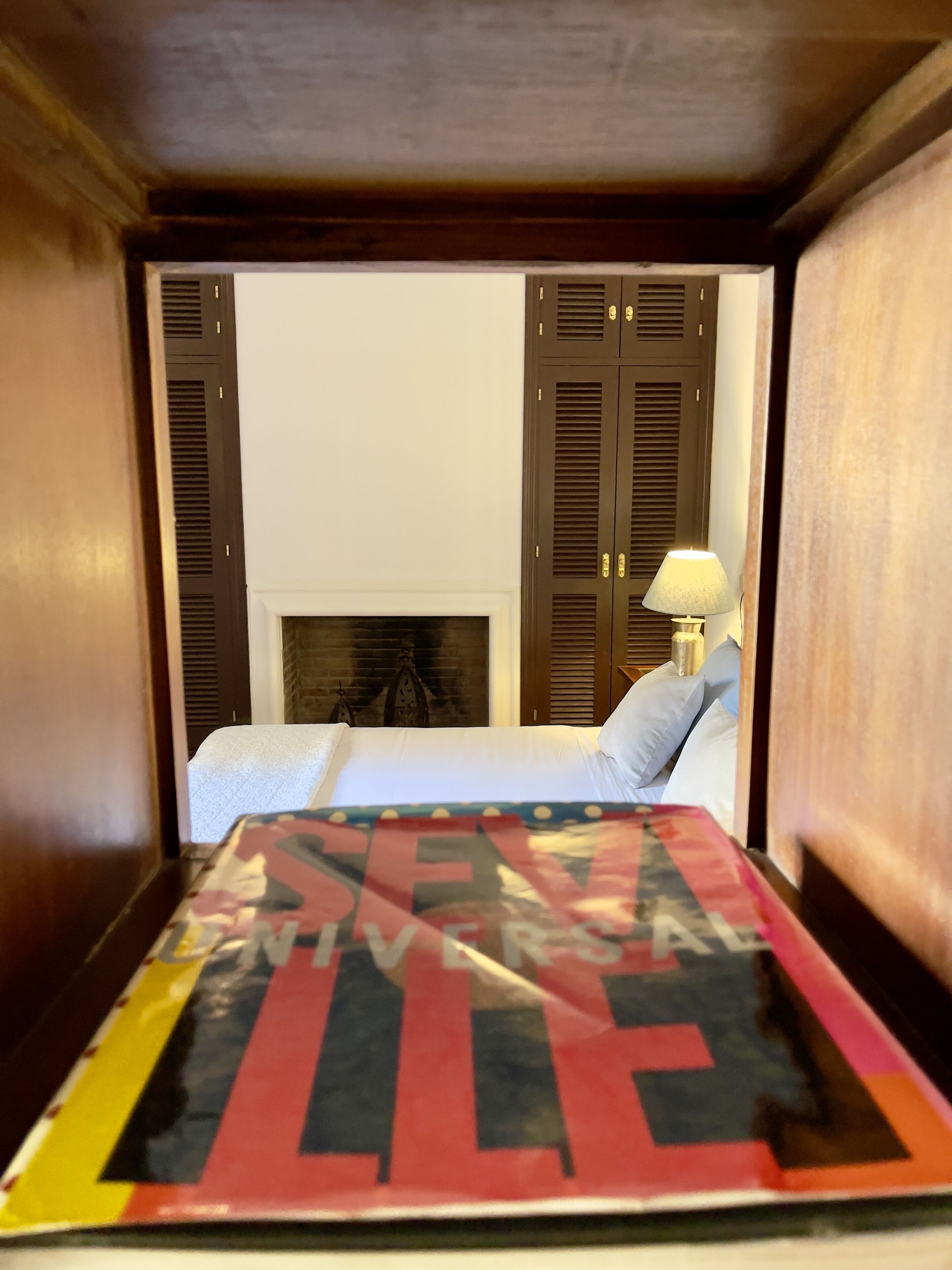A hotel room with a bed, a fireplace, and wooden shutters.