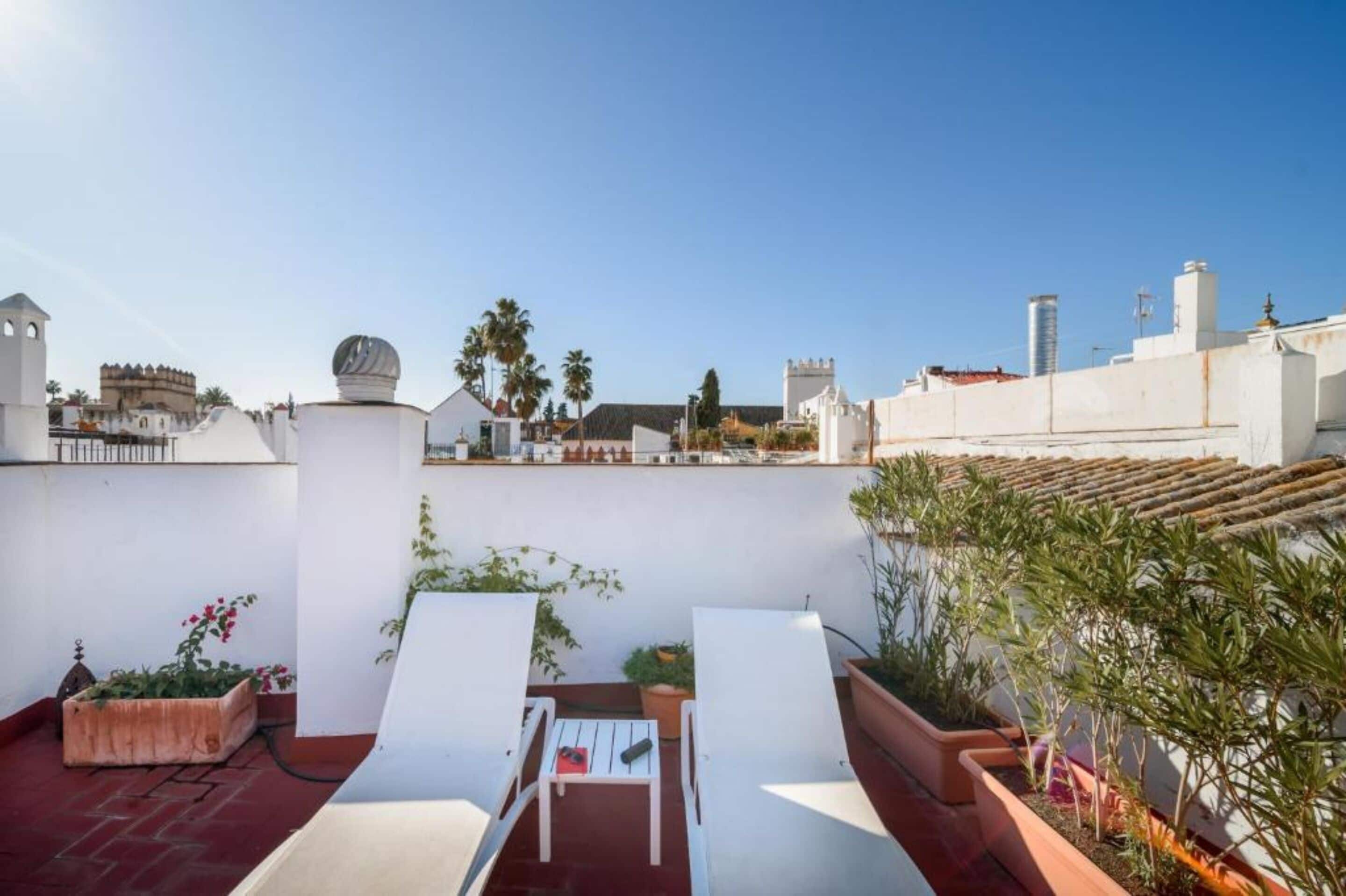 Una terrazza sul tetto con sedie bianche, un tavolino e piante in vaso.