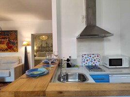 A compact kitchen with a sink, a microwave, and a dining area with a table set for two.