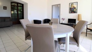 Un espace repas moderne avec une table ronde, quatre chaises, un luminaire suspendu et un tableau au mur.