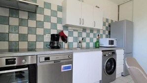 Une petite cuisine équipée comprenant un lave-vaisselle, un four à micro-ondes et un lave-linge.
