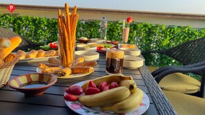 A table with various food items including bread, pastries, and fruits, and a bottle of water. -  Pyramids View Guest House (Giza)